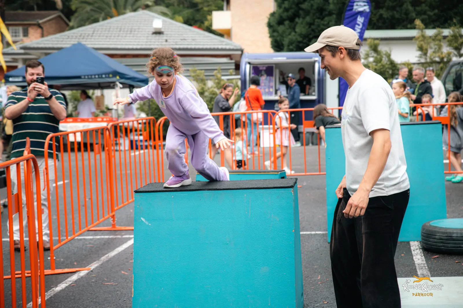 A KongQuest coach spotting a child over an obstacle at an Open Festival