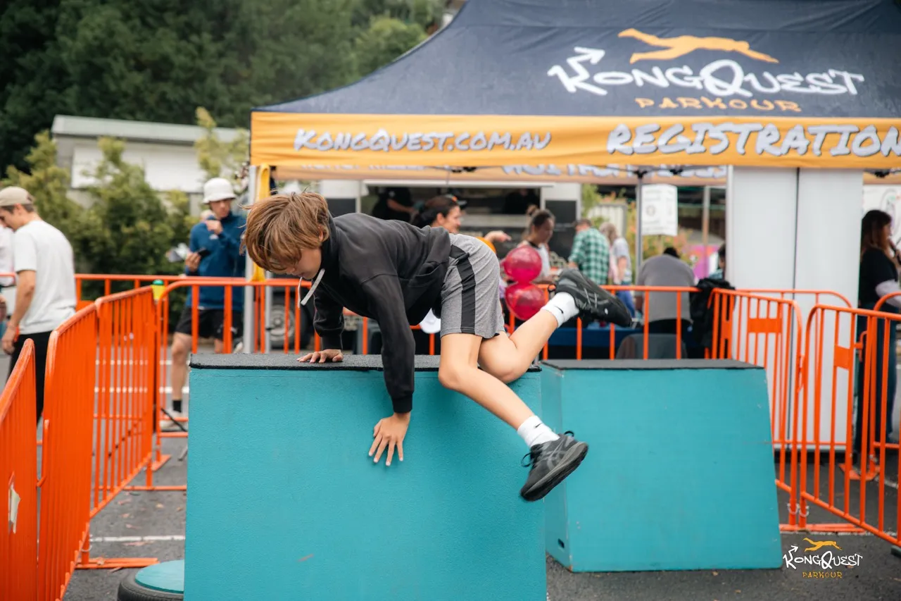A child clearing a box beside the branded KongQuest registration tent