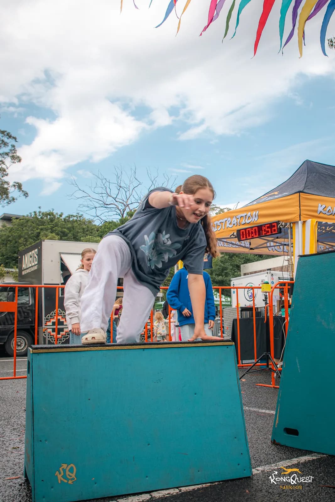 A girl launching off a box on the Open Festival course under festival bunting