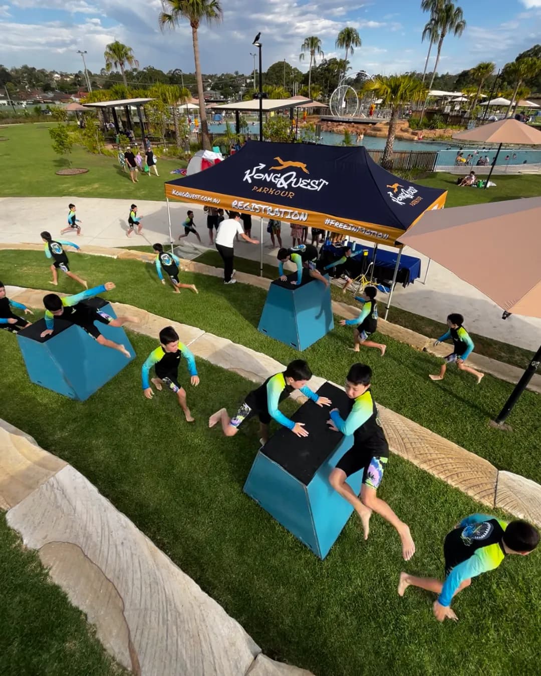 A full class of kids in KongQuest rashies running the Pop-Up parkour course on the grass